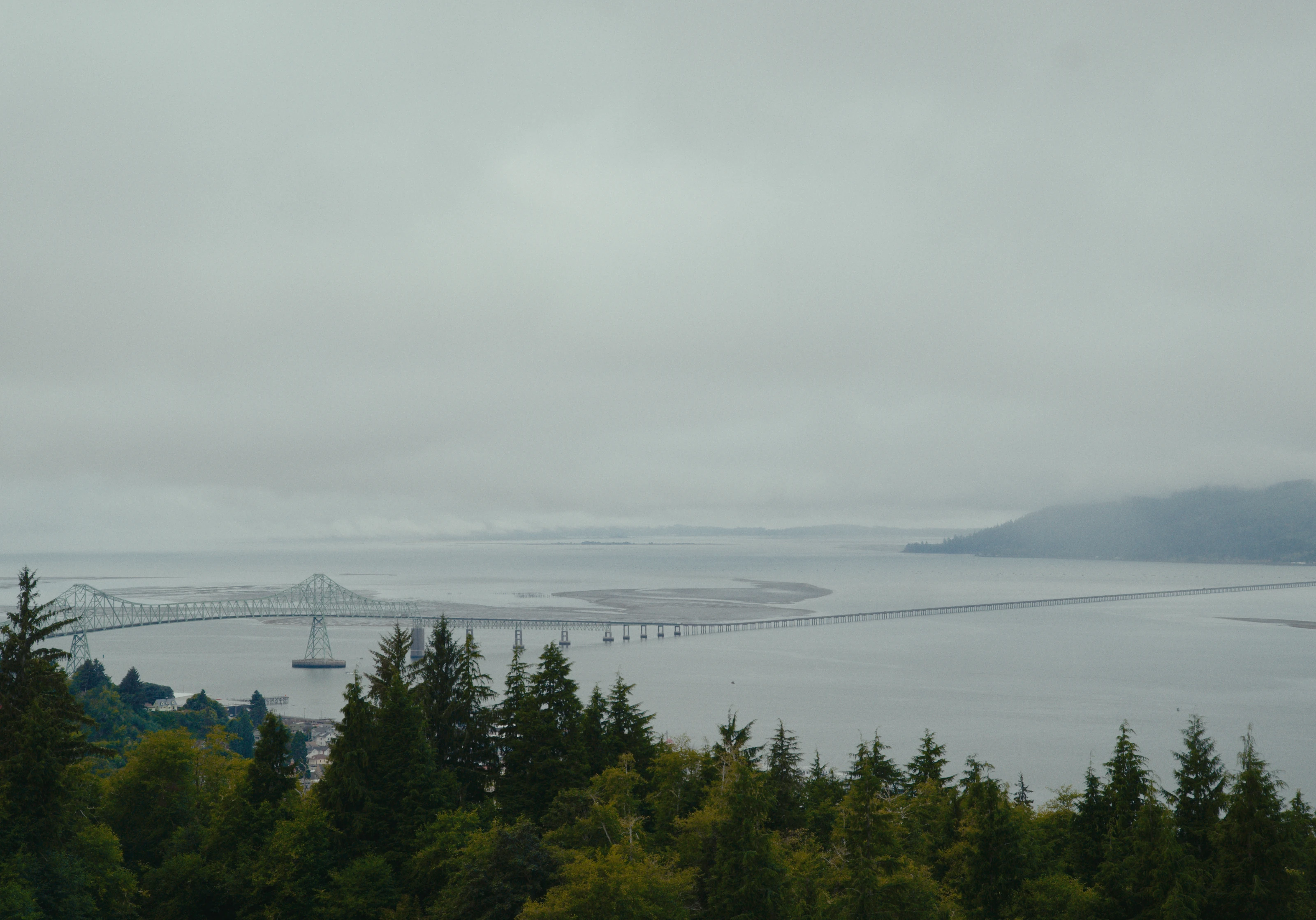 A wide misty view across a bridge and water.