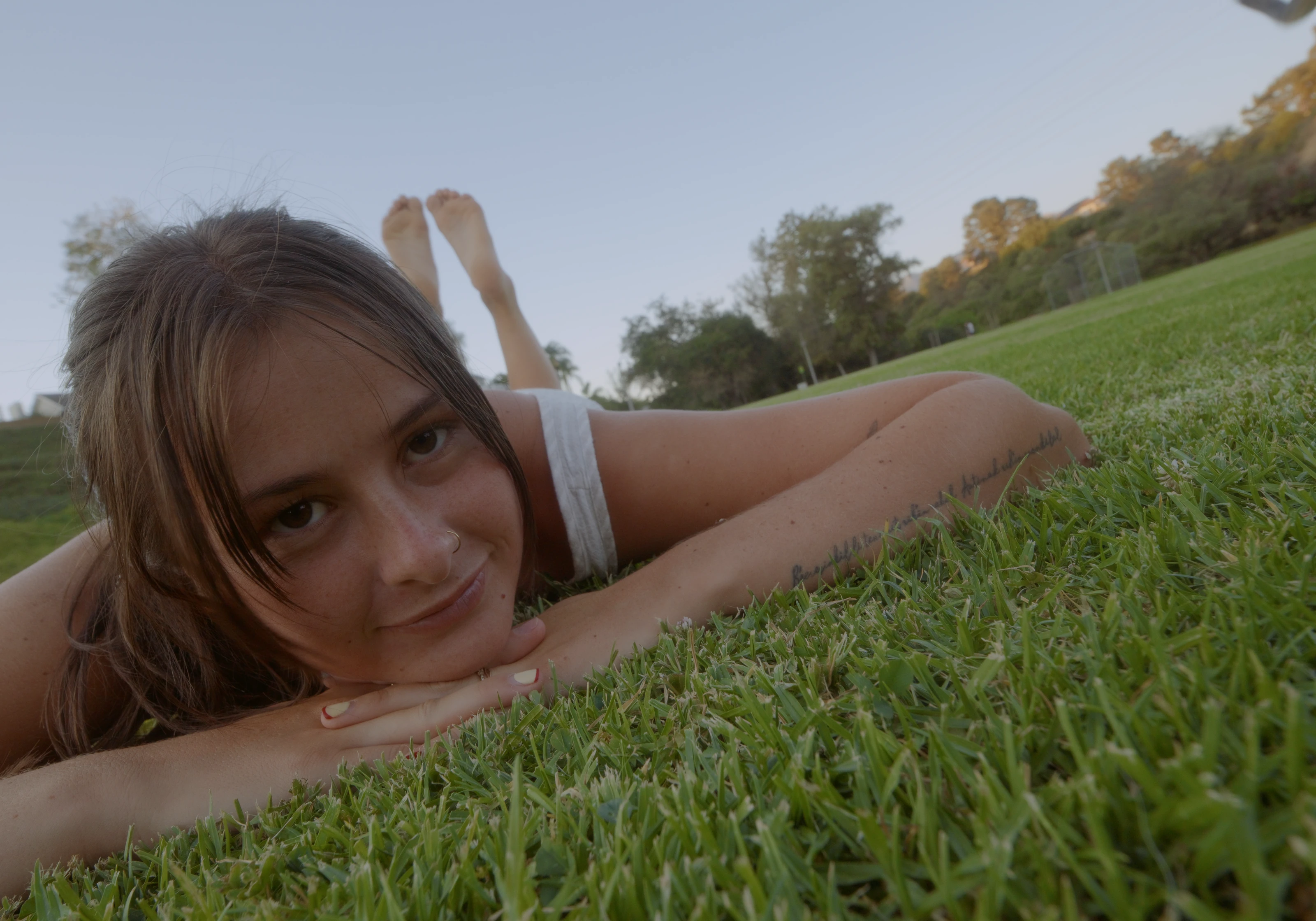 A woman resting close to the grass in a sunlit field.