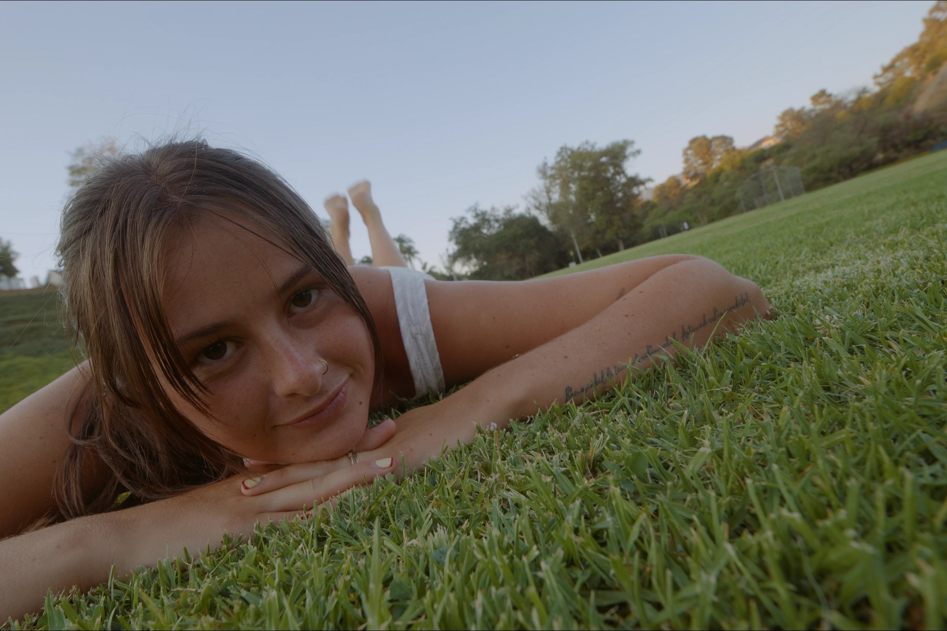 A woman resting on grass in warm evening light.