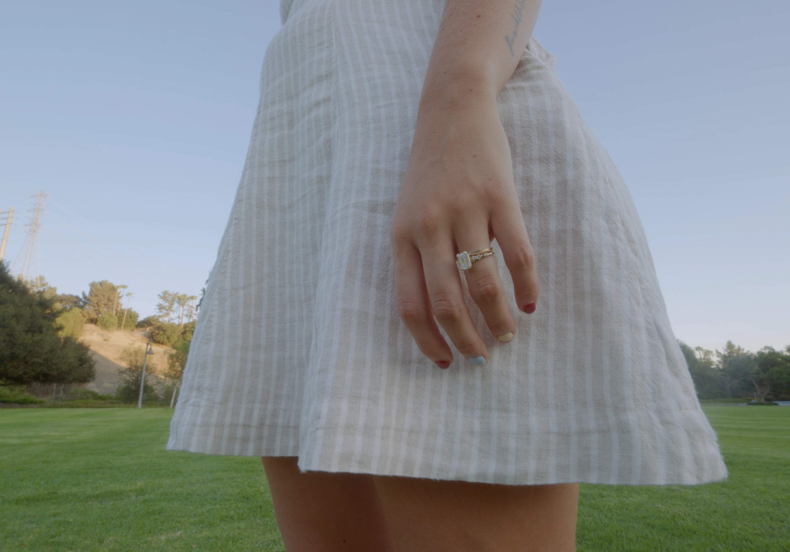 A woman in a white dress standing in a sunlit field.