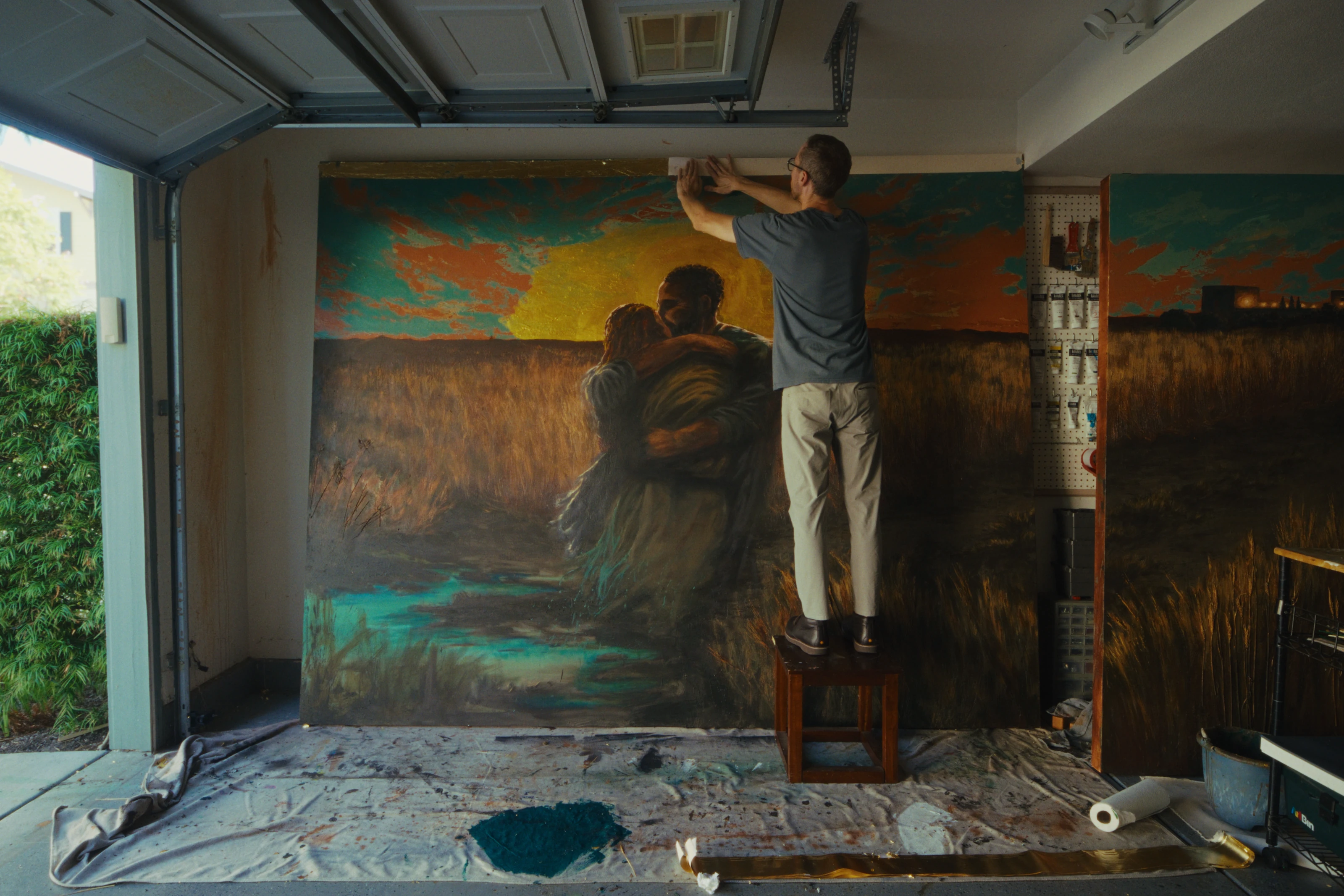 An artist working on a large mural in a garage studio.